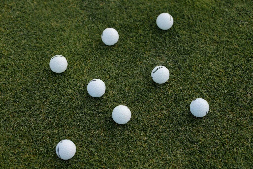 A visually appealing composition of scattered white golf balls on a lush green grass field.
